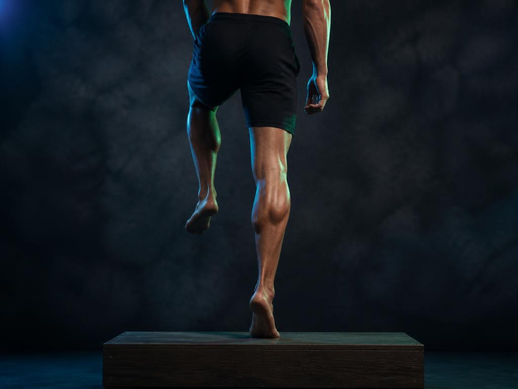 Barefoot single-leg calf raise on a step in low blue light